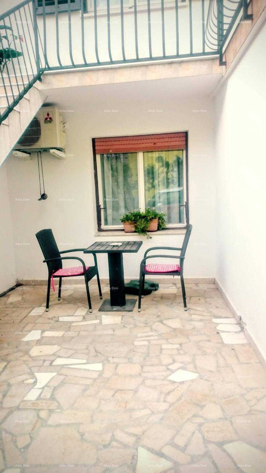 Kleine gepflasterte Terrasse mit Tisch und Stühlen unter einem Balkon.