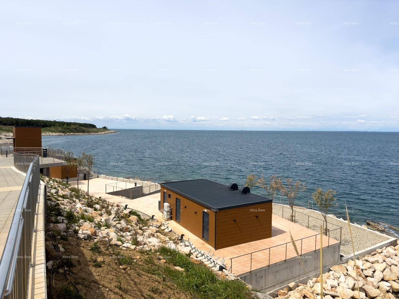 Mehrere moderne Gebäude mit Holzverkleidung entlang der felsigen Küste mit Meerblick.
