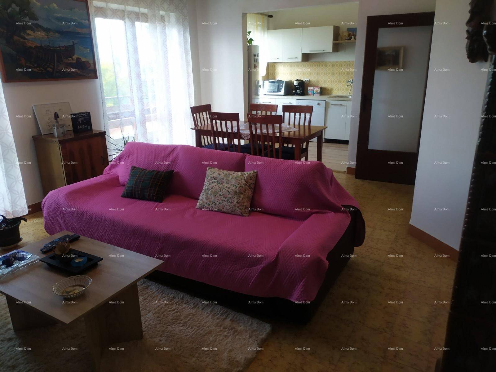 Gemütlicher Wohn- und Essbereich mit rosa Sofa, Holztisch und offener Küche im Hintergrund.