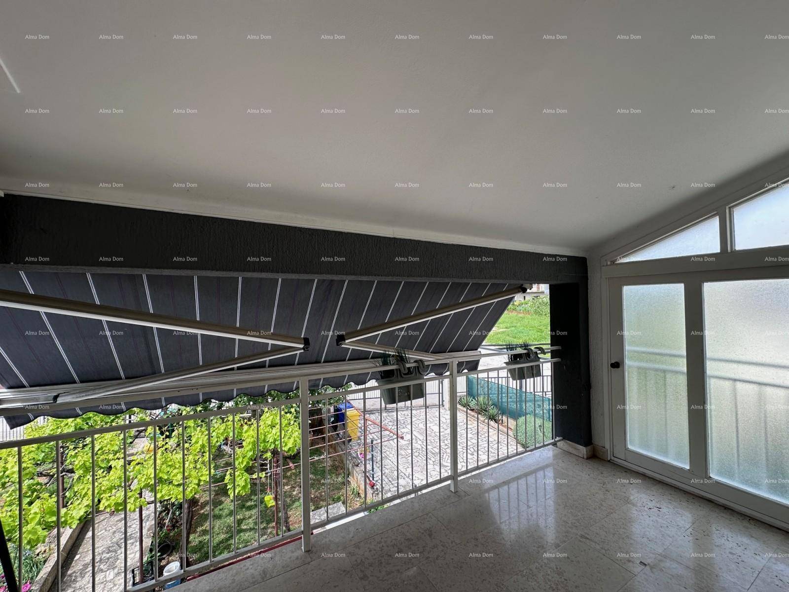 Überdachter Balkon mit ausfahrbarer Markise, weißem Geländer und Blick ins Grüne.
