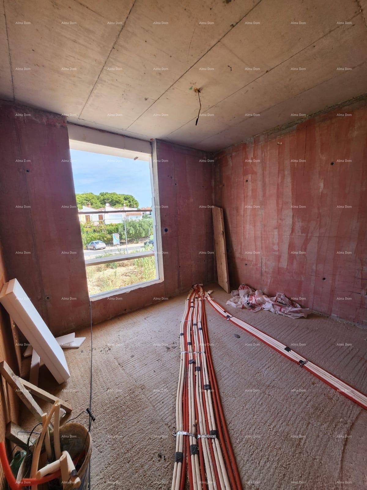 Rohbau eines Raumes mit großem Fenster, unverputzten Wänden und vorbereiteten Elektroinstallationen.