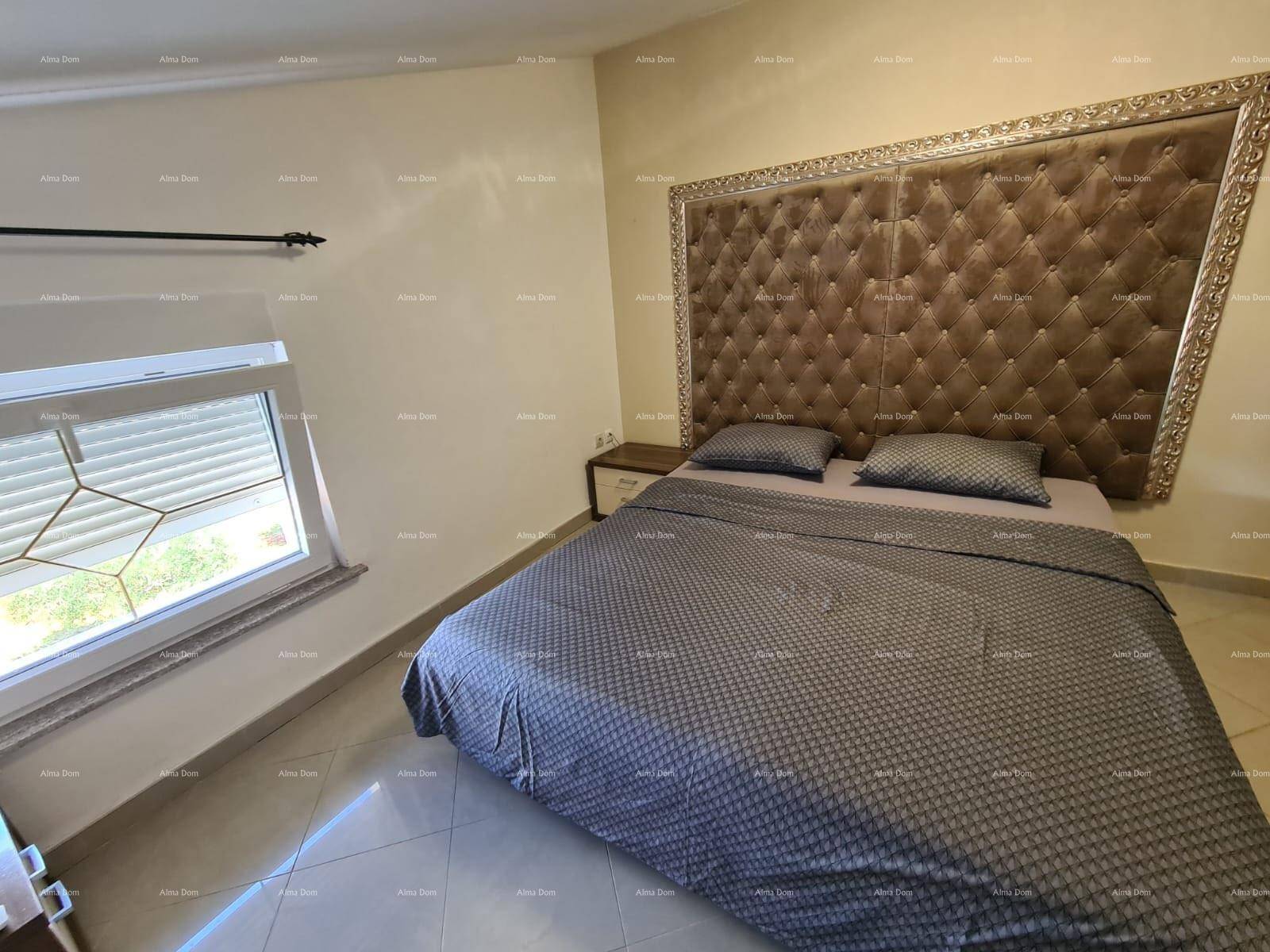 Schlafzimmer mit großem Bett, gepolstertem Kopfteil und Fenster für Tageslicht.