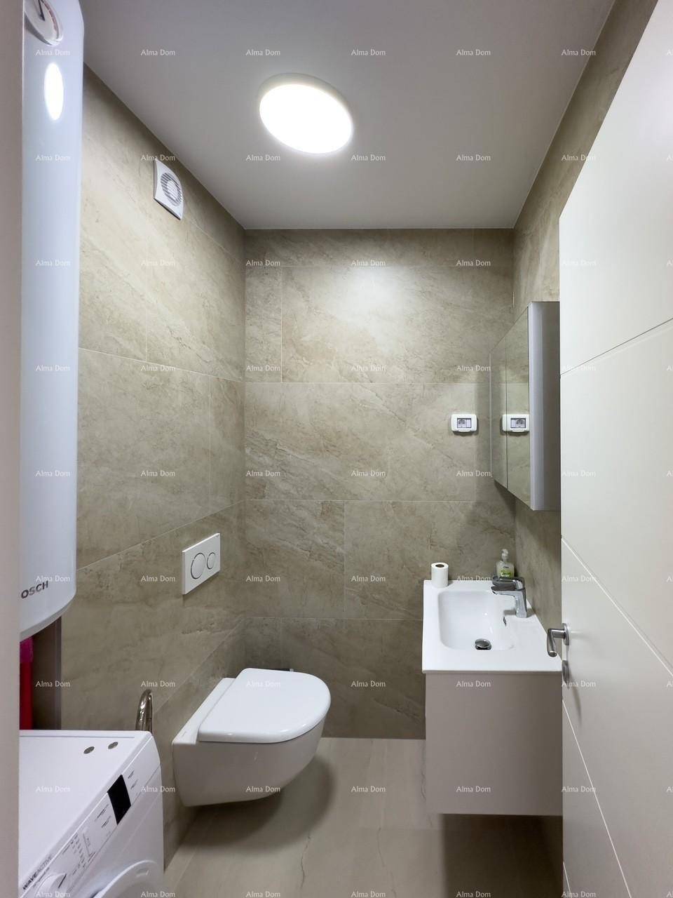 Kleines Badezimmer mit WC, Waschbecken, Waschmaschine und Abluftventilator, ausgestattet mit Fliesen.