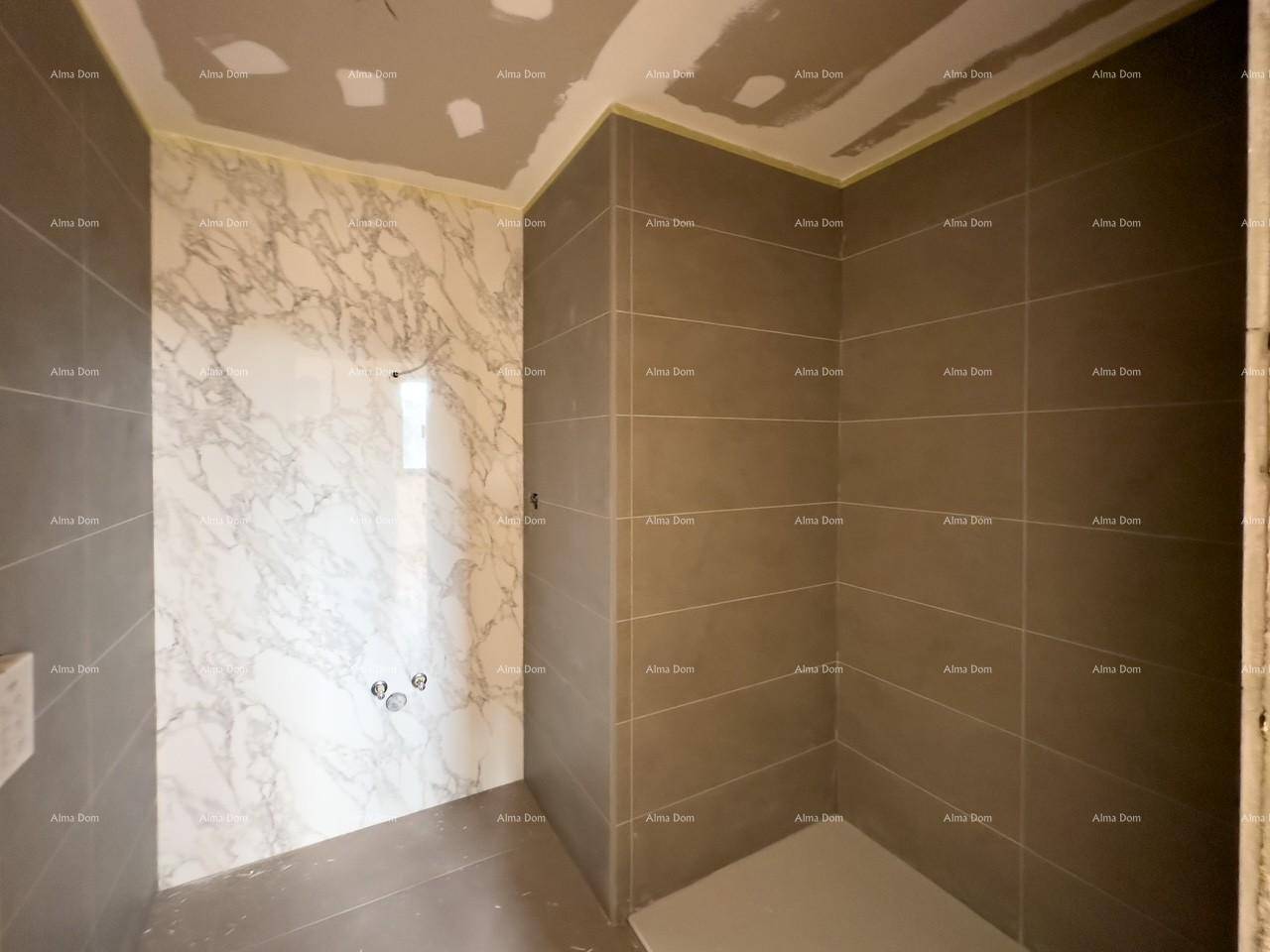 Unfertiges Badezimmer mit grauen Wandfliesen und einer Duschwanne.