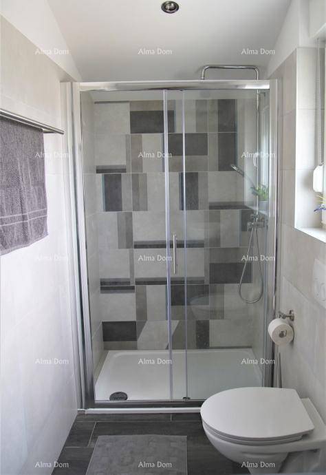 Helles Badezimmer mit Duschkabine, WC und Fenster, ausgestattet mit modernen Fliesen.