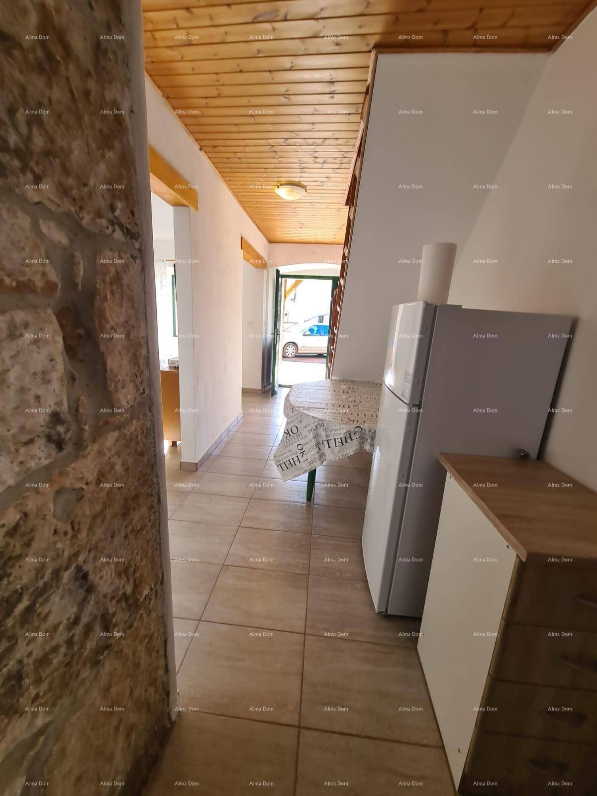 Eingangsbereich mit Fliesenboden, Holzdecke und einem Kühlschrank am Ende des Flurs.