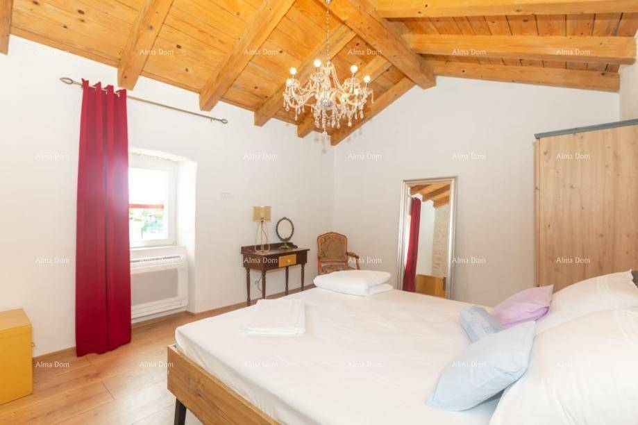 Helles Schlafzimmer mit Holzbalkendecke, Parkettboden und rotem Vorhang am Fenster.