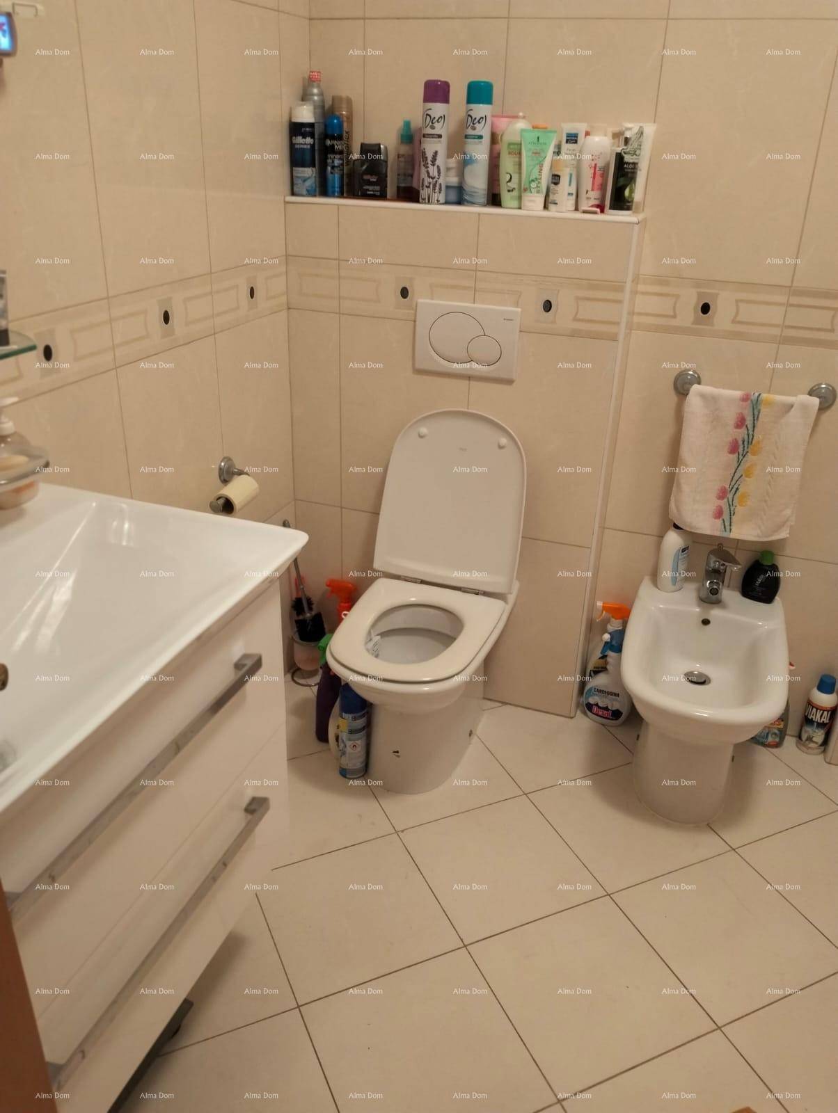 Helles Badezimmer mit WC, Bidet und Waschbecken, ausgestattet mit beigefarbenen Fliesen.