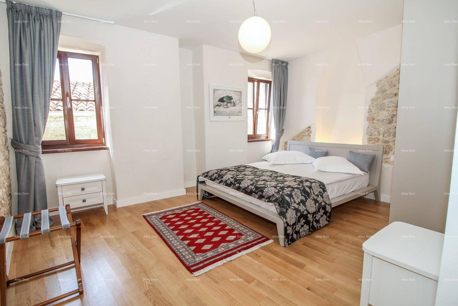 Helles Schlafzimmer mit Holzboden, Doppelbett und freigelegter Steinwand als Akzent.