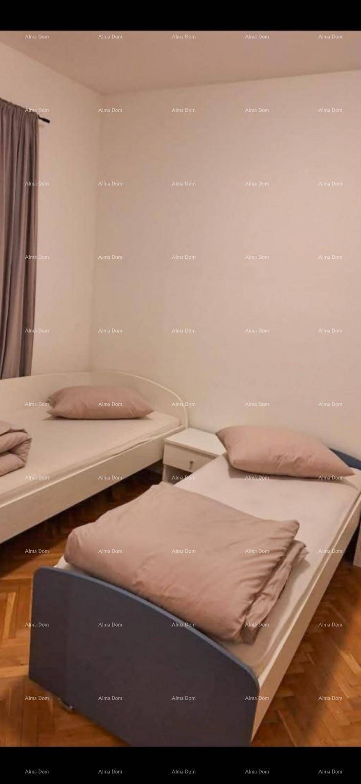 Schlafzimmer mit zwei Einzelbetten, Holzboden und schlichten Vorhängen an einem Fenster.