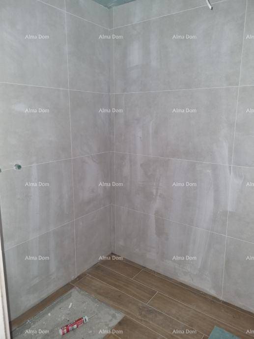 Badezimmer im Bau mit grauen Wandfliesen und holzfarbenem Bodenbelag.