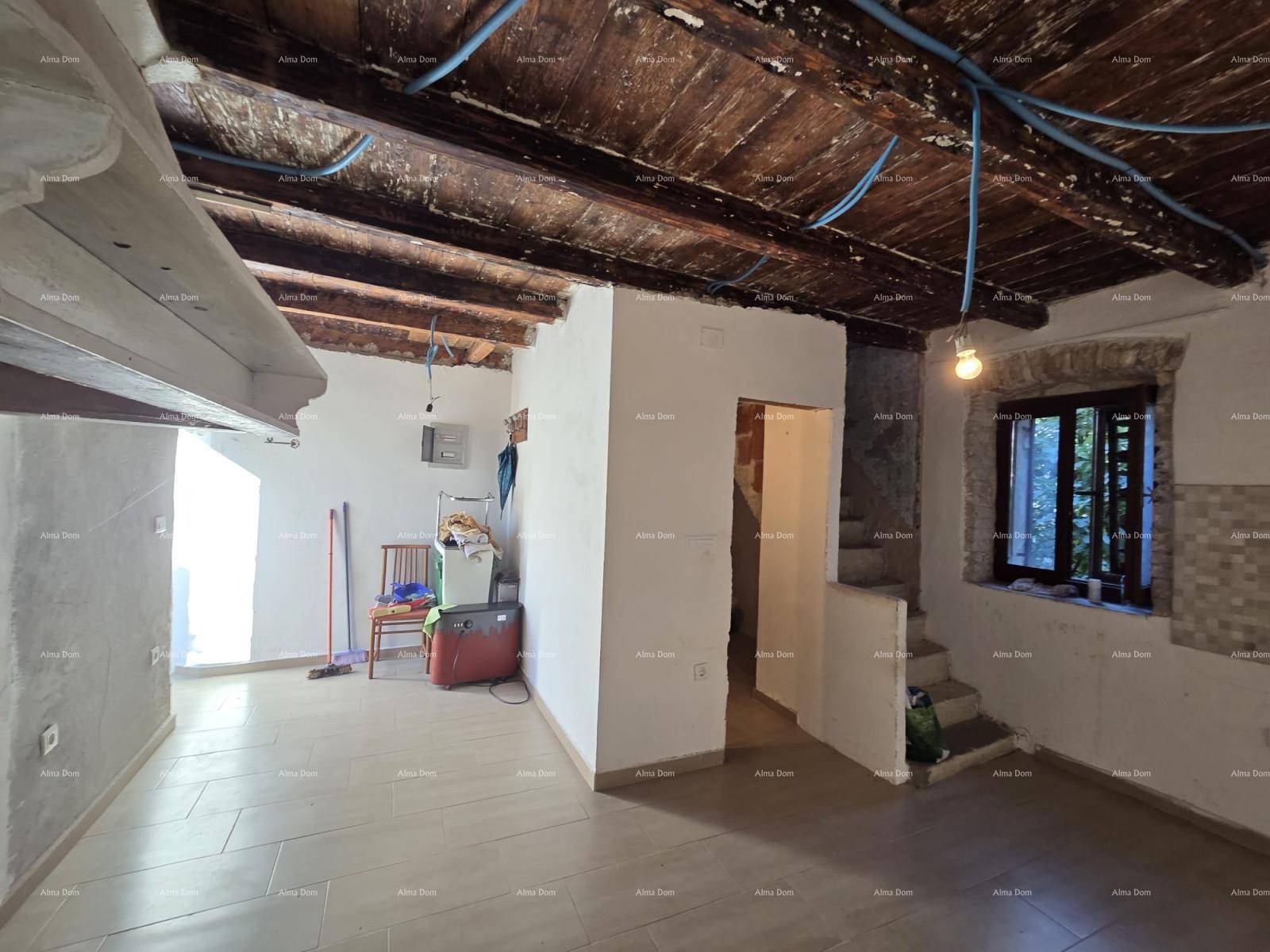 Großer Raum im Rohbau mit Fliesenboden, sichtbaren Holzbalken und Vorbereitungen für Installationen.