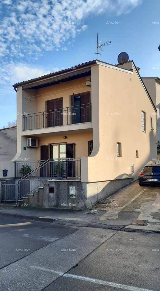 Zweistöckiges Haus mit Balkonen und einer Zufahrt, ein Auto ist davor geparkt.