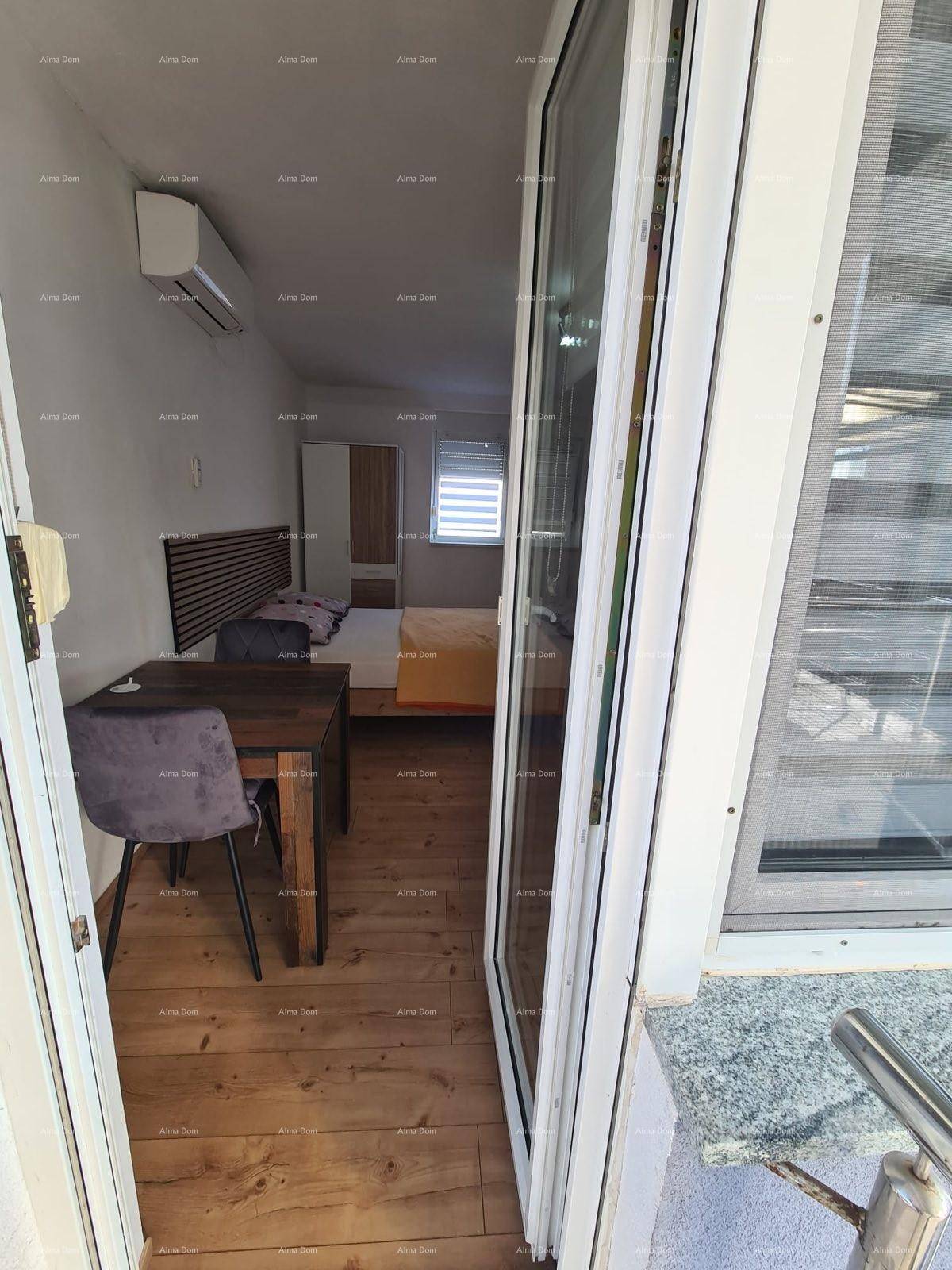 Schlafzimmer mit Doppelbett, Esstisch und Zugang zu einem Balkon mit Glasfront.
