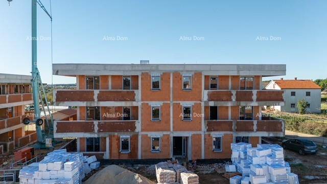Vorderansicht eines Gebäudes im Rohbau mit Fensteröffnungen und Baustelle unter blauem Himmel.