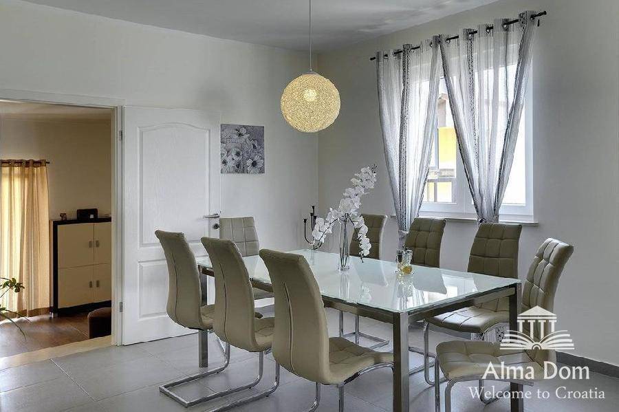 Eleganter Essbereich mit großem Tisch, modernen Stühlen und stilvoller Hängelampe.