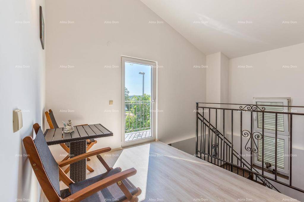 Heller Flur im Obergeschoss mit kleinem Sitzbereich und Zugang zu einem französischen Balkon.