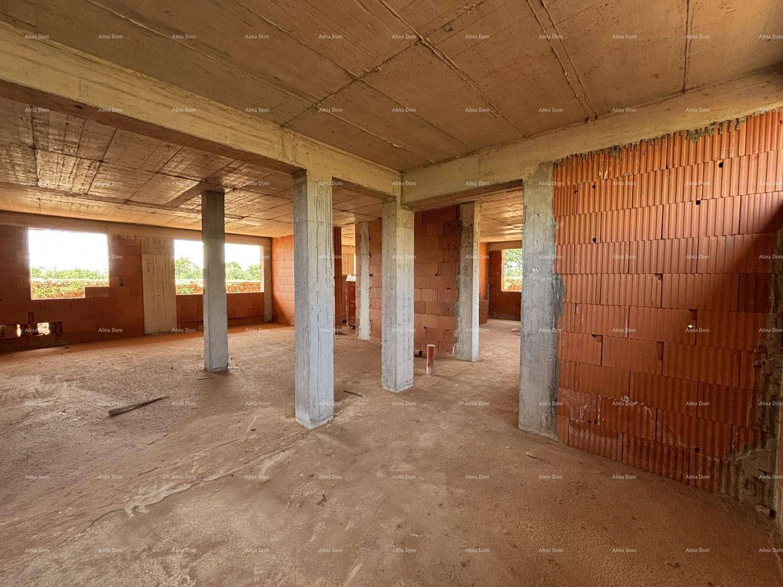 Der Innenbereich im Rohbau mit Betonstützen und Fensterausschnitten, die Tageslicht hereinlassen.