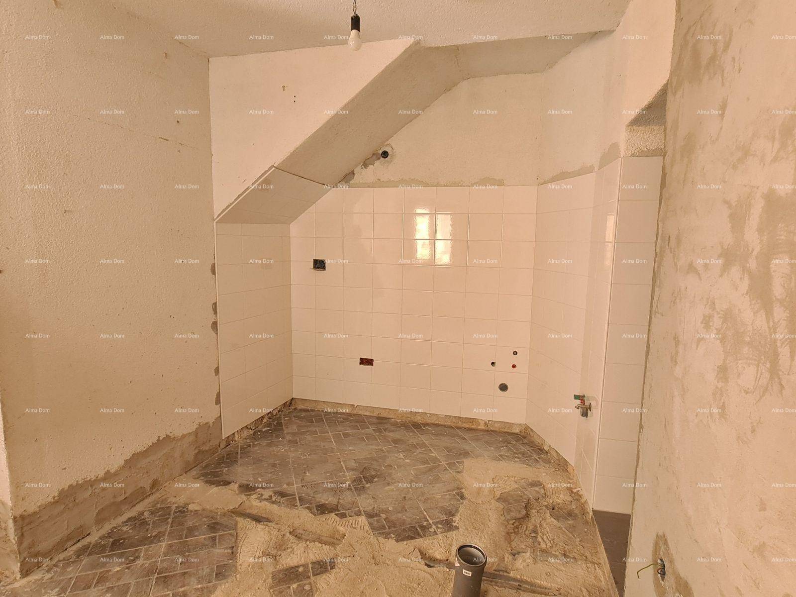 Küche im Rohbau mit gefliesten Wänden, vorbereiteten Anschlüssen und einer Dachschräge.