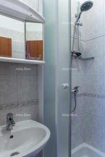 Helles Badezimmer mit Duschkabine, Waschbecken und Spiegelschrank, gefliest in neutralen Tönen.