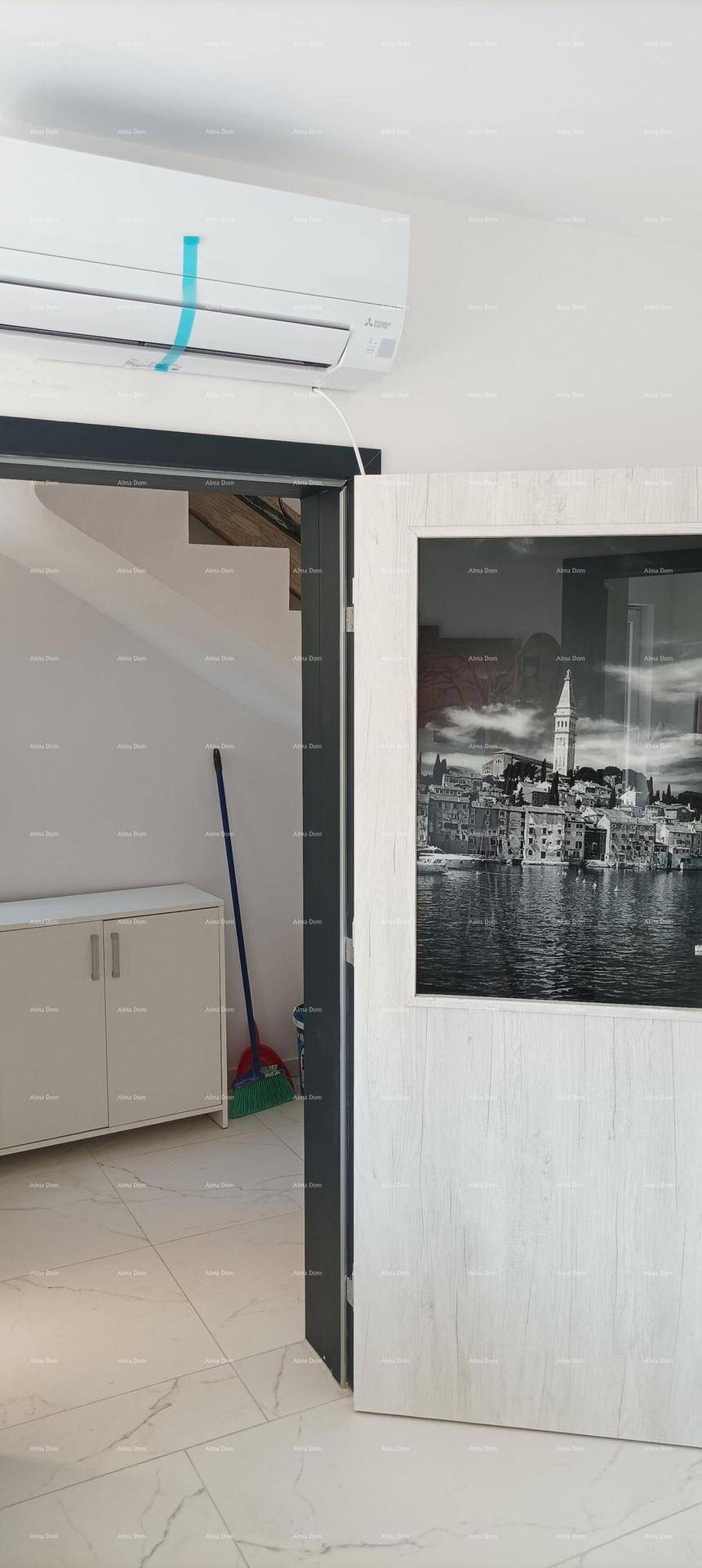 Heller Flurbereich mit Klimaanlage, Fliesenboden und einem Bild an der Wand.