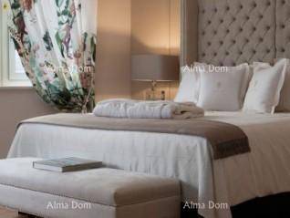 Geräumiges Schlafzimmer mit luxuriösem Bett, gepolstertem Kopfteil und einer bequemen Sitzbank.