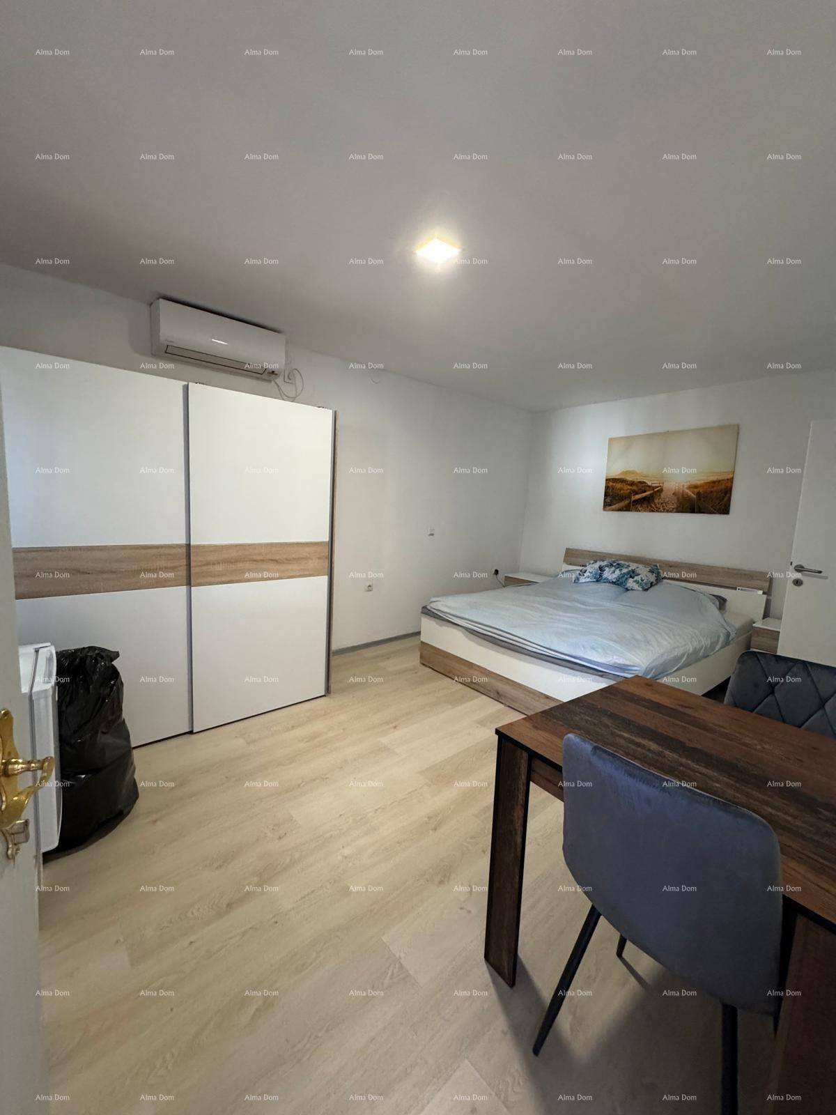 Helles Schlafzimmer mit Doppelbett, großem Kleiderschrank und Esstisch, mit Laminatboden.
