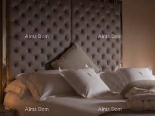 Großes Bett mit einem hohen, gepolsterten Kopfteil und weichen weißen Kissen für Komfort.