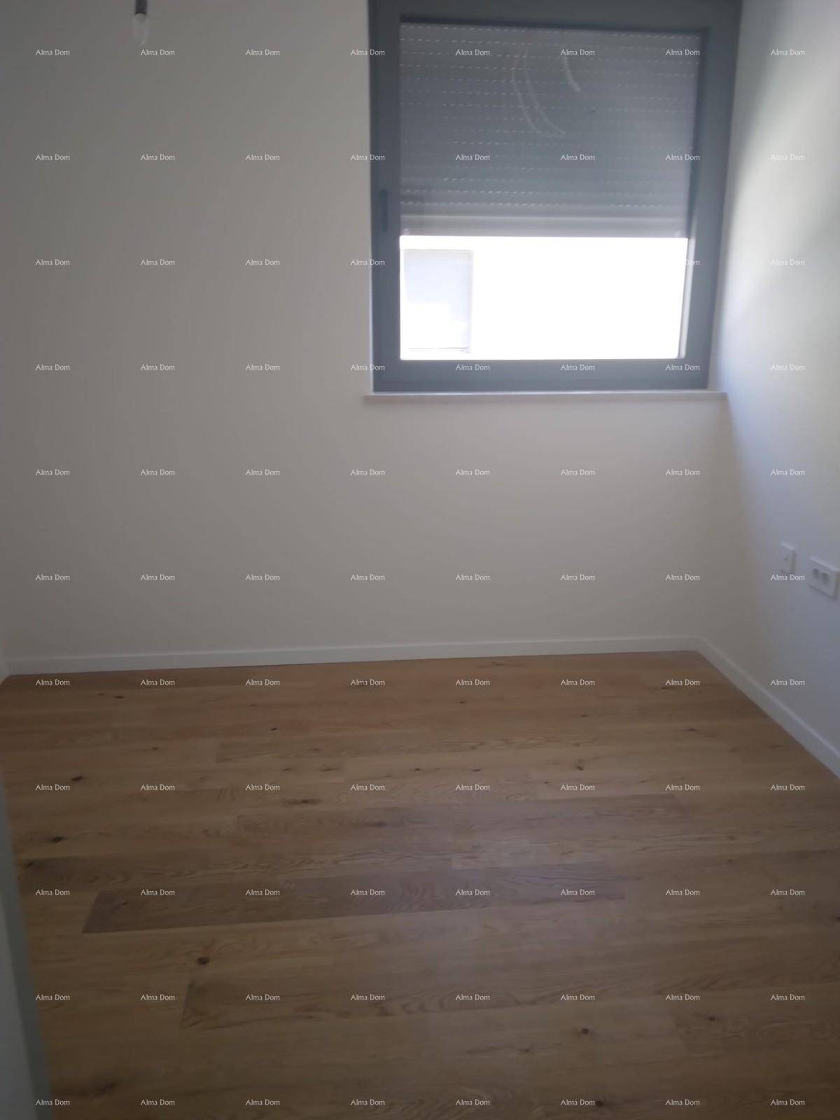 Leeres Schlafzimmer mit hellem Holzfußboden und einem Fenster mit Rollladen.