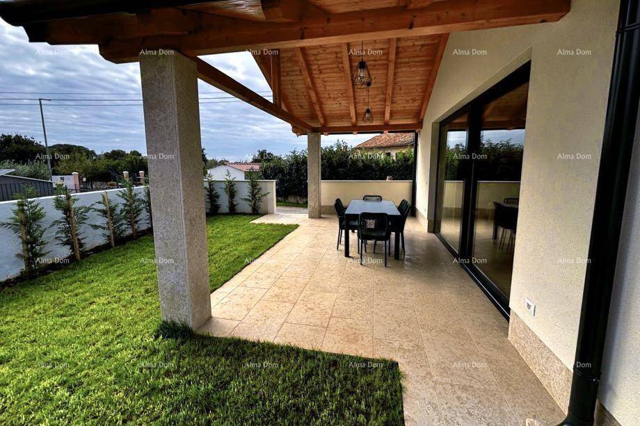 Überdachte Terrasse mit gepflastertem Boden, Säulen und angrenzender Rasenfläche.