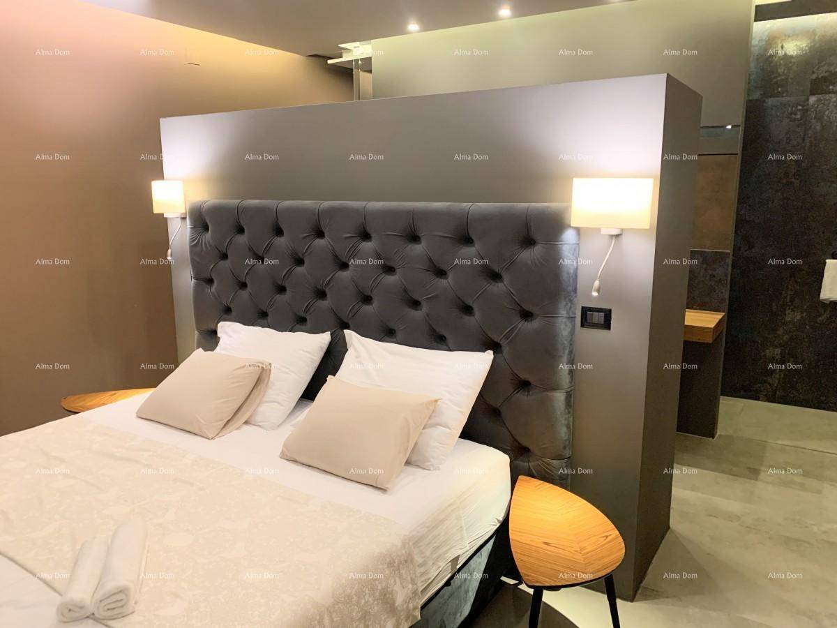 Modernes Schlafzimmer mit grauem Polsterbett und offenem Zugang zu einem stilvollen Badezimmerbereich.
