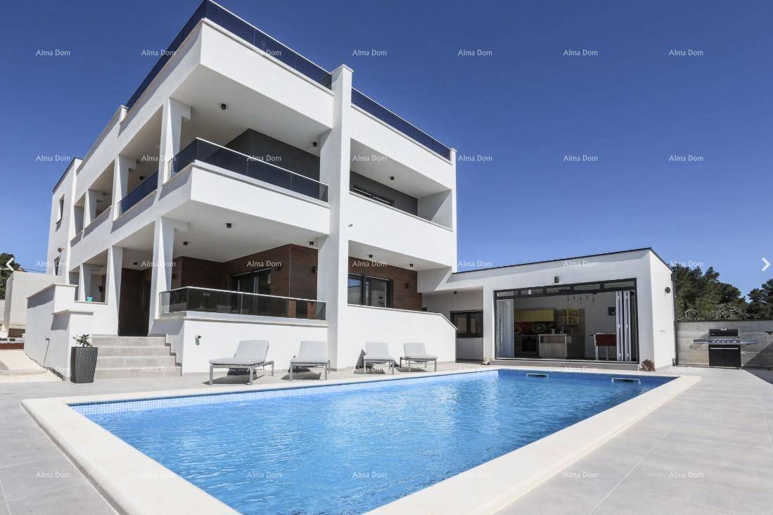 Moderne weiße Villa mit mehreren Balkonen, großem Pool und angrenzendem Außenbereich.