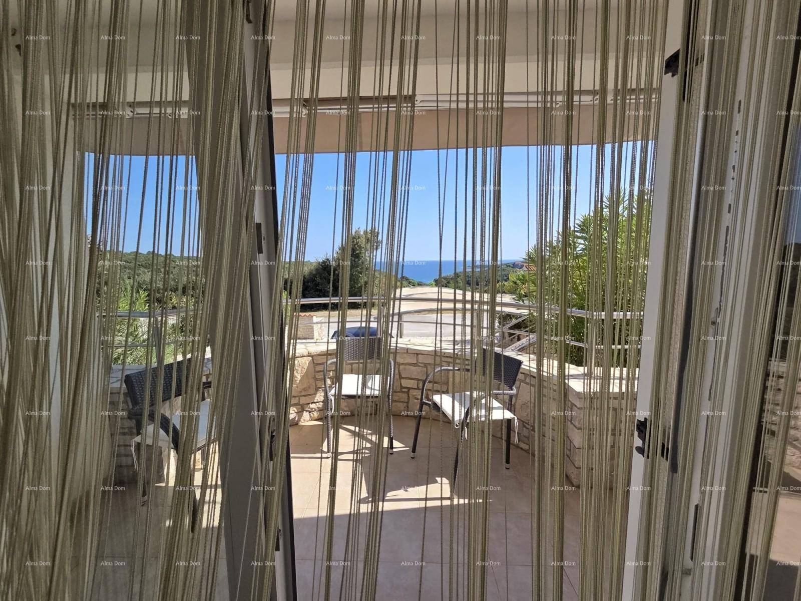 Innenansicht mit Blick durch Vorhänge auf eine möblierte Terrasse und das weite Meer.