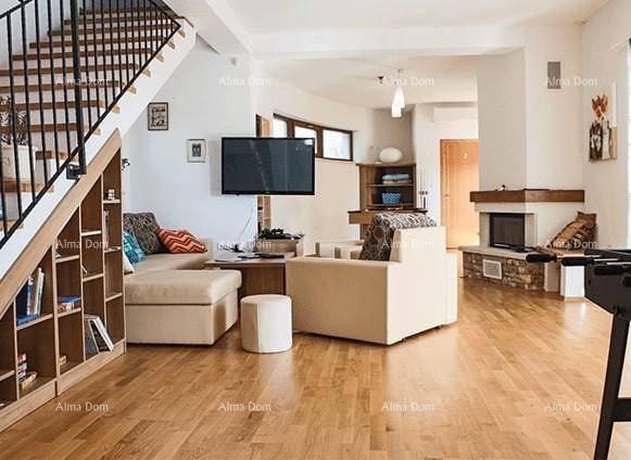 Großzügiges Wohnzimmer mit Kamin, Treppe, Bücherregal und bequemen Sitzgelegenheiten.