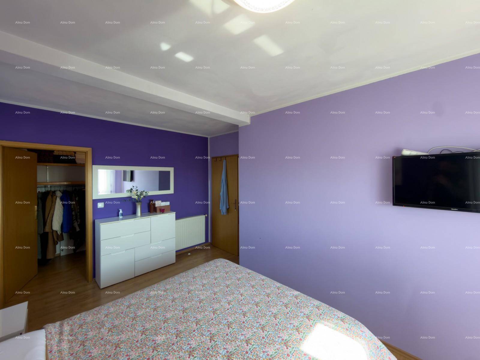 Schlafzimmer mit lila Wänden, Holzboden und Zugang zu einem begehbaren Kleiderschrank.