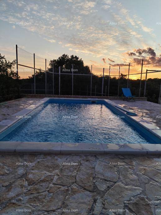 Außenpool mit gepflasterter Terrasse und Blick auf die umliegende Landschaft bei Sonnenuntergang.
