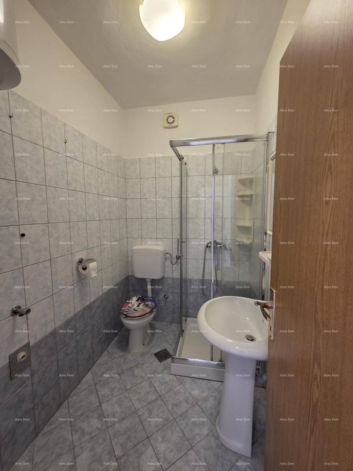 Badezimmer mit blauen und grauen Fliesen, Duschkabine, WC und Waschbecken.