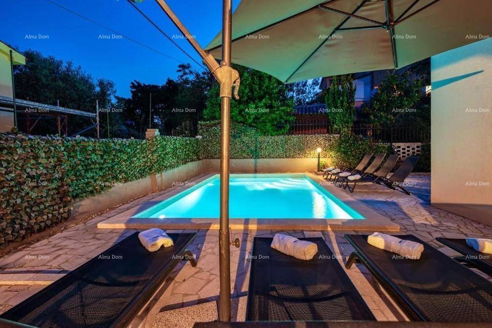 Gemütlicher Poolbereich bei Nacht mit Liegestühlen, Sonnenschirm und Handtüchern.