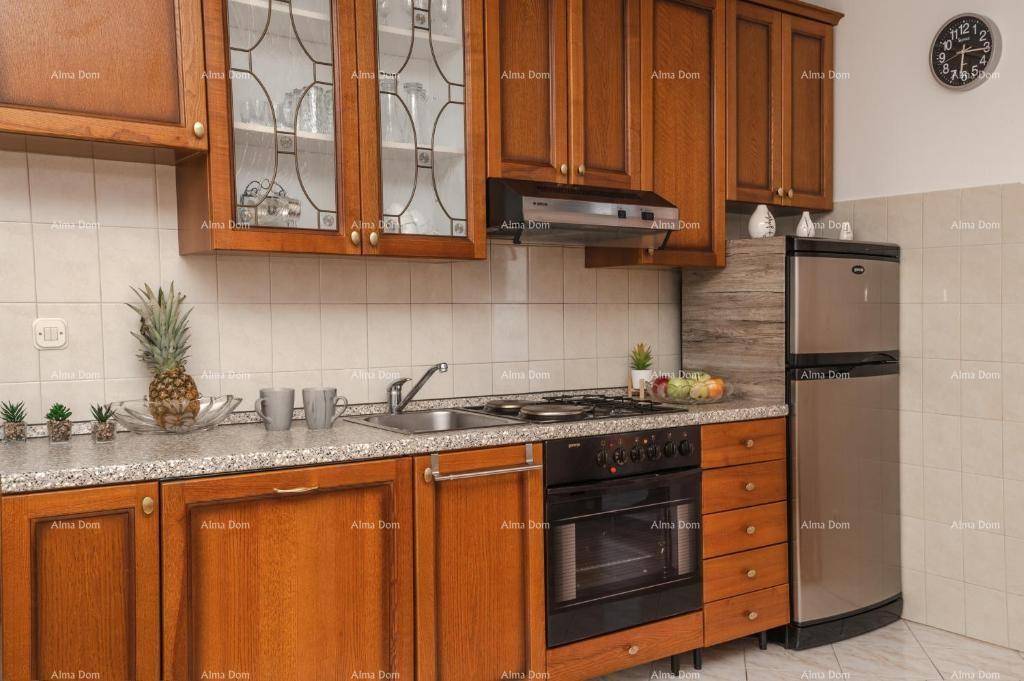 Funktionale Küche mit Holzschränken, Gasherd, Backofen und einem Kühlschrank aus Edelstahl.