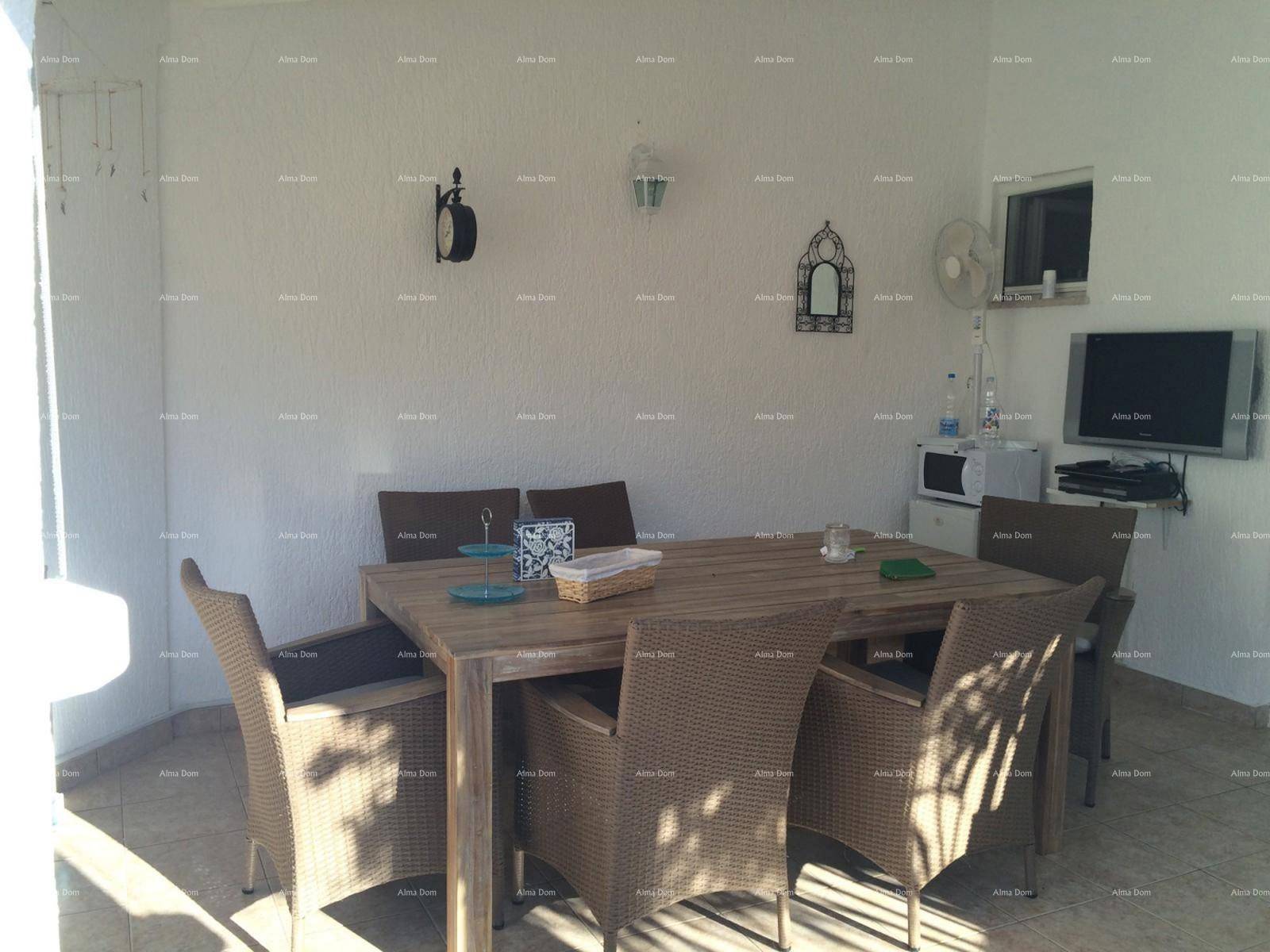 Überdachte Terrasse mit Rattanmöbeln und Esstisch, ideal für Mahlzeiten im Freien.