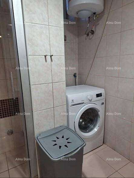 Kleines Badezimmer mit Duschkabine, Waschmaschine und hellen Fliesen an Wänden und Boden.