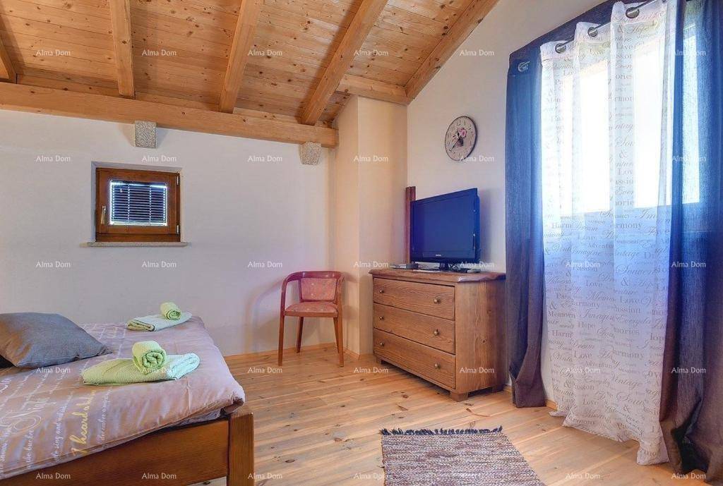 Schlafzimmer mit Holzbalkendecke, Einzelbett und Kommode mit Fernseher.
