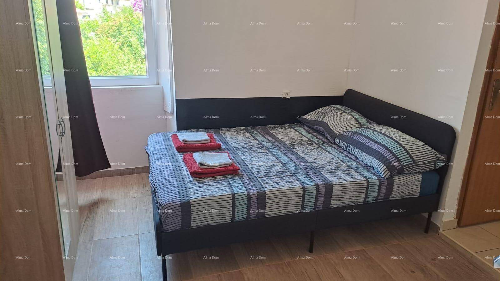 Schlafzimmer mit Doppelbett und Kleiderschrank, ausgestattet mit einem Fenster und dunklen Vorhängen.