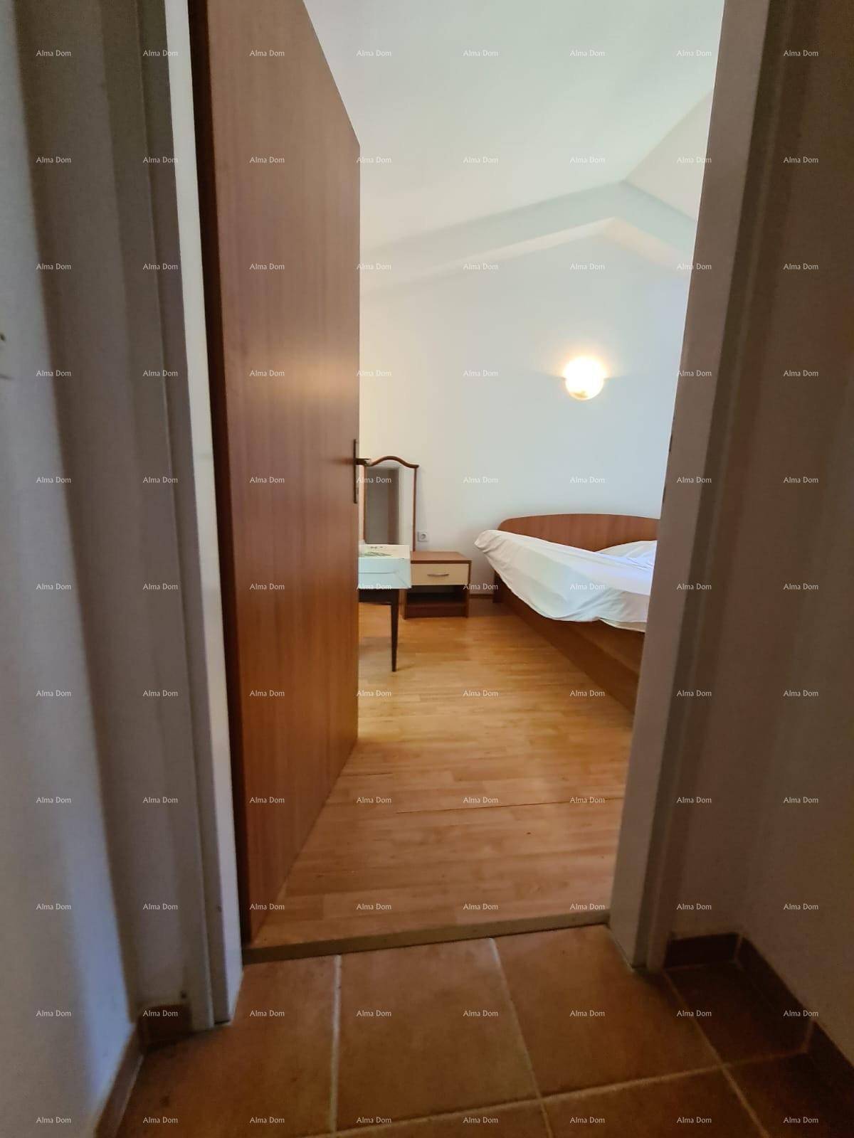 Blick durch eine Tür in ein Schlafzimmer mit Bett und hellem Holzboden.