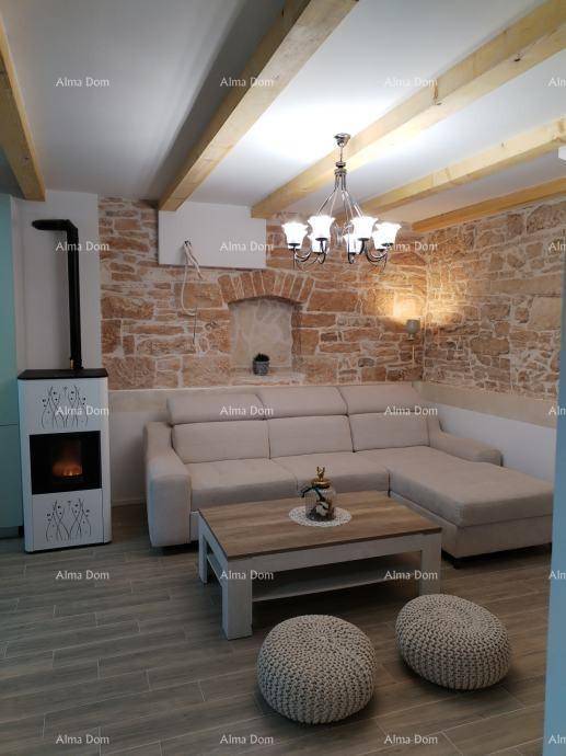 Gemütliches Wohnzimmer mit Steinwänden, Holzbalken und modernem Kaminofen, perfekt für entspannte Stunden.