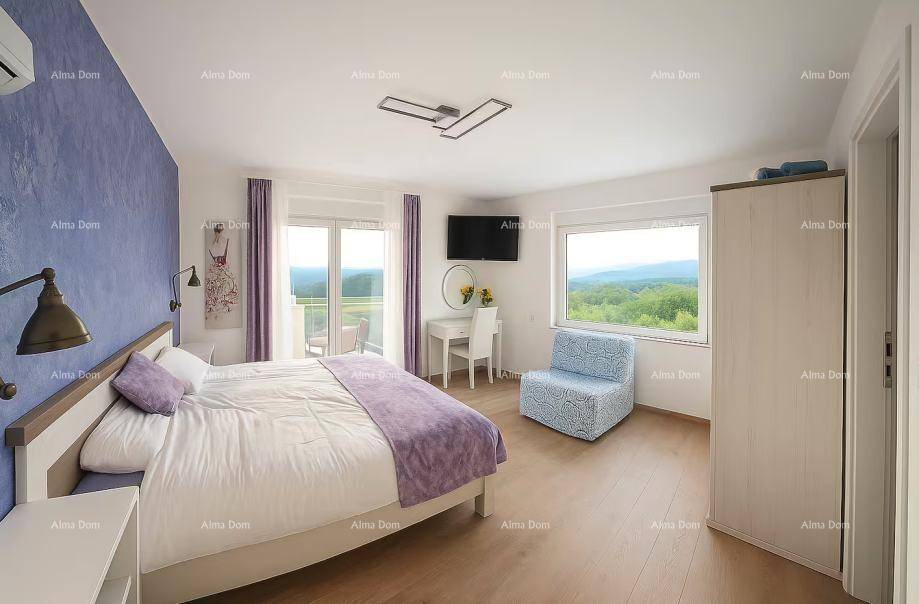 Helles Schlafzimmer mit lila Akzentwand, Balkonzugang und weitem Blick ins Grüne.