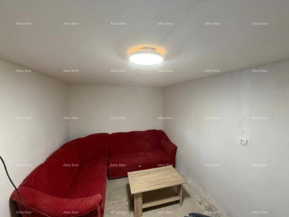 Gemütliches Wohnzimmer mit einem roten Ecksofa und einem einfachen Holztisch in der Mitte.