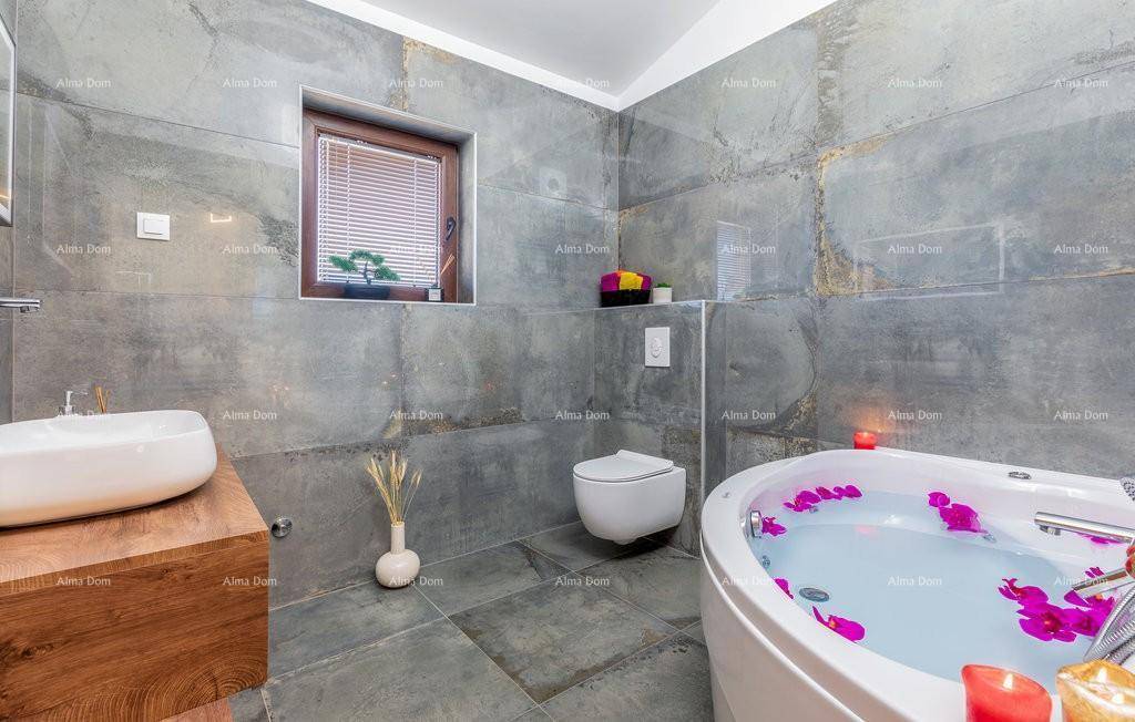 Modernes Badezimmer mit grauen Fliesen, freistehender Badewanne und einem Waschbecken auf Holzunterschrank.