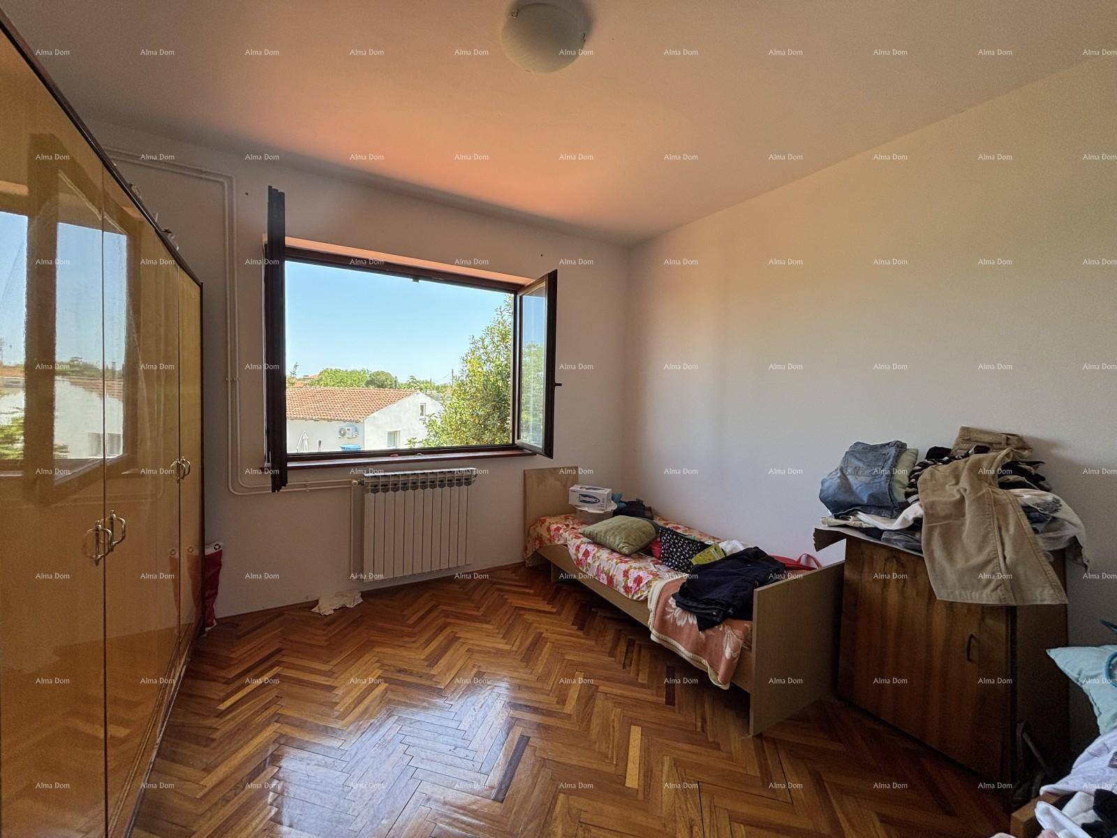 Schlafzimmer mit Einzelbett, Holzschrank und großem Fenster mit Blick ins Grüne.