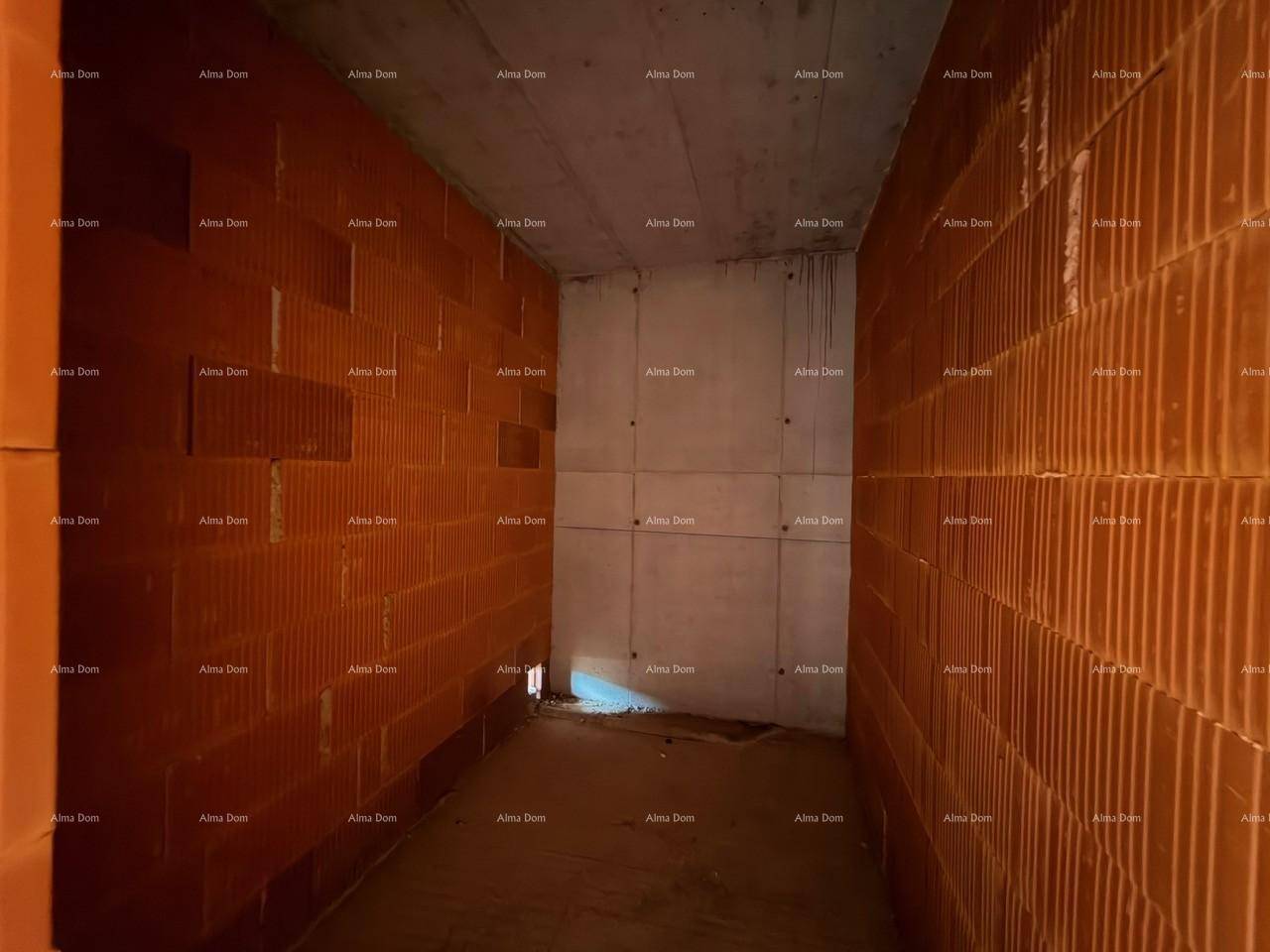 Schmaler Rohbau-Raum mit Ziegelwänden und Betonboden, der auf den Innenausbau wartet.